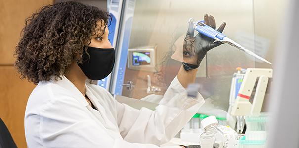 Female college student wearing a white robe in a biology lab