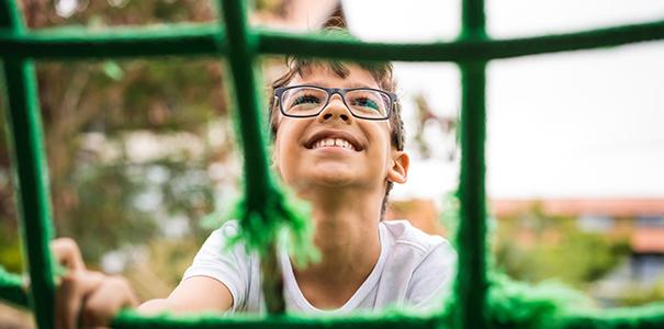 male child smiling and climbing playground equipment