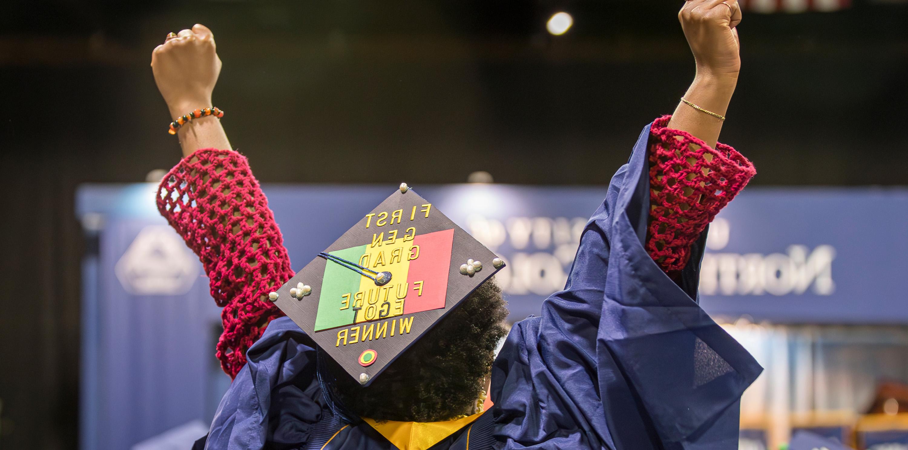 A graduate with their arms in the air in celebration