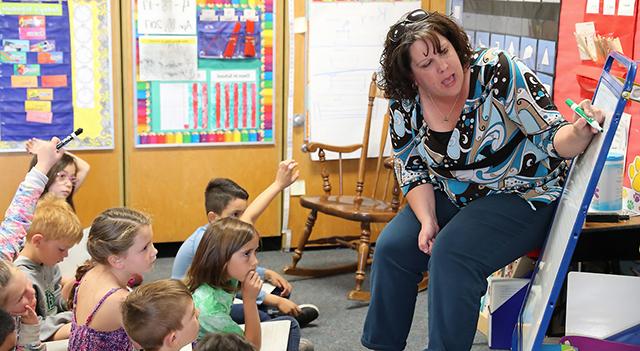 Teacher teaching children their lessons in school