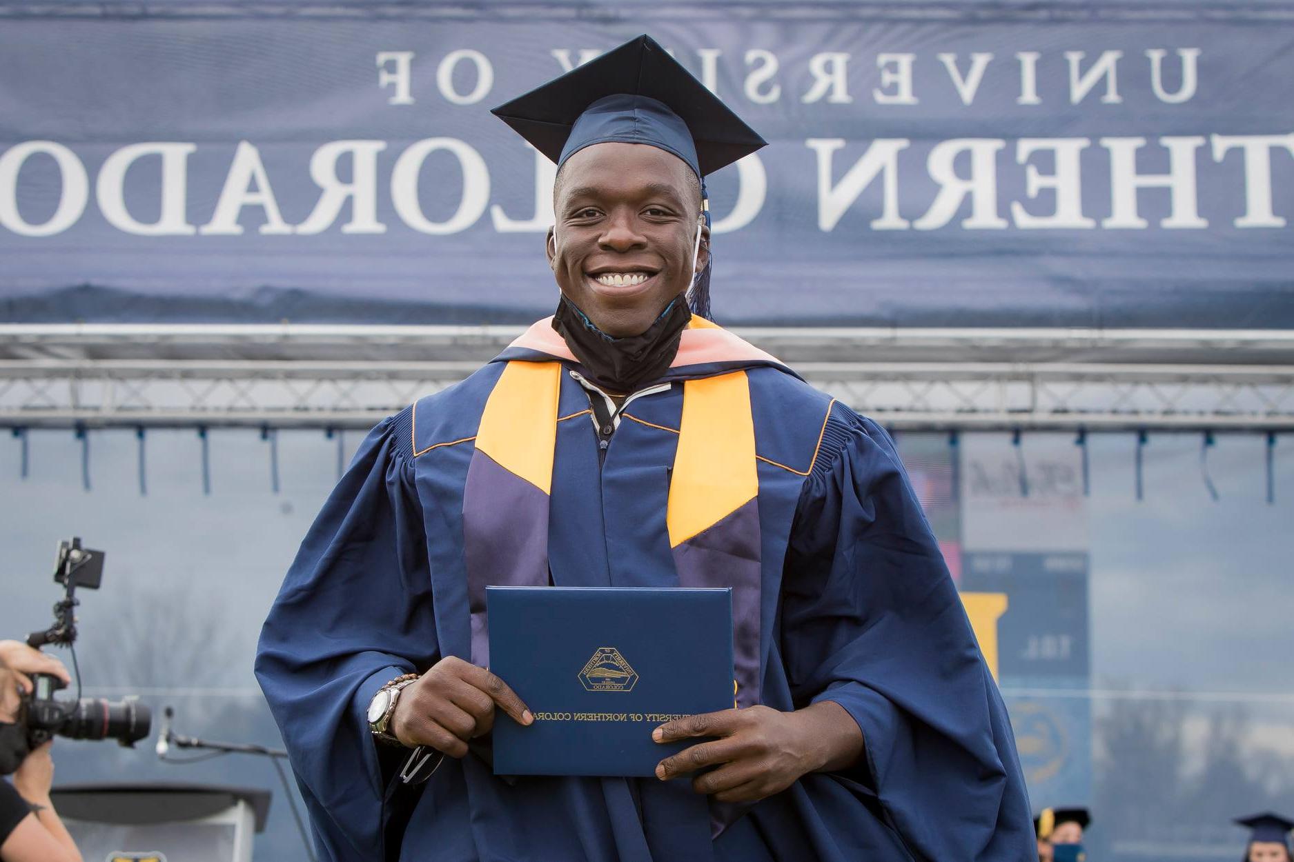 科罗拉多公共卫生学院 student Fisayo Awolaja accepting graduation certificate. Best Grad Schools 2023 US 皇冠app安卓下载安装 logo in top left corner of image. 